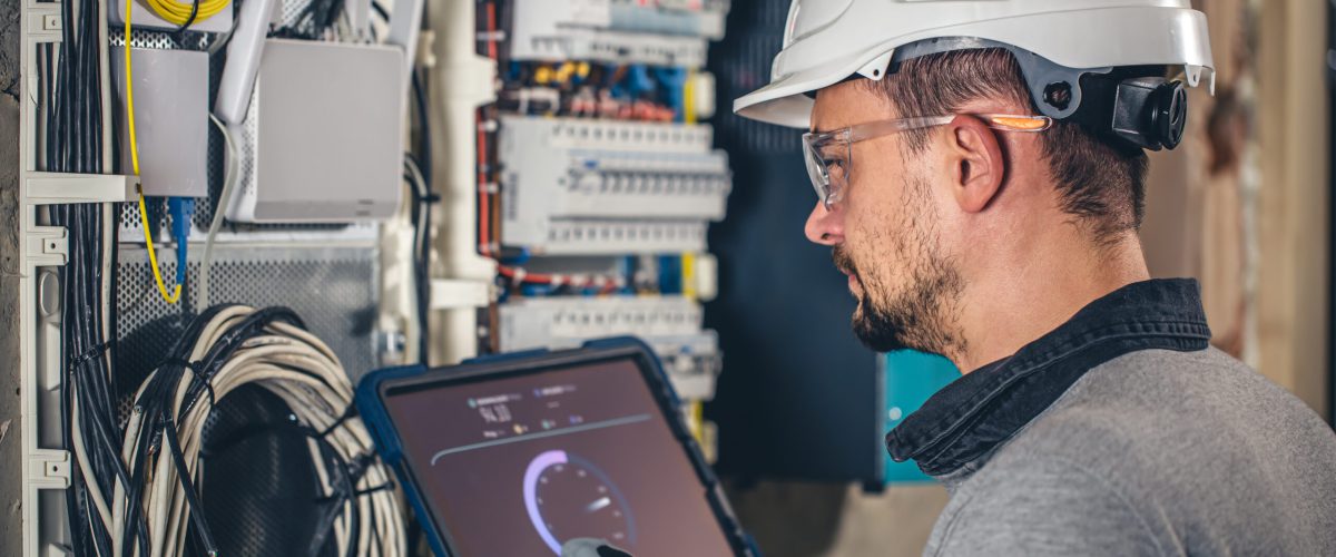Man, an electrical technician working in a switchboard with fuses. Installation and connection of electrical equipment.